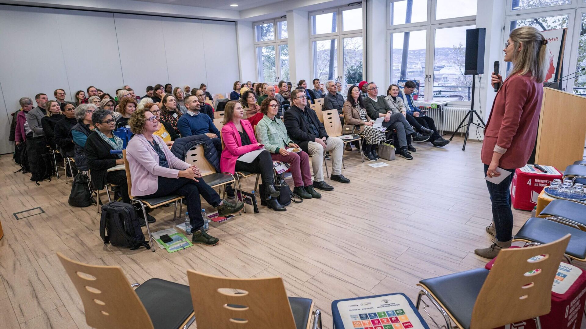 Mirjam Hitzelberger stehend mit Mikrofon vor den Teilnehmer*innen der Herbstkonferenz 2023