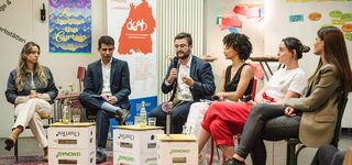 6 Personen sitzen auf einem Podium und diskutieren miteinander
