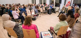 Diskussionsrunde vorne mit 8 Personen und im Hintergrund viele Zuschauer*innen auf der Herbstkonferenz 2023